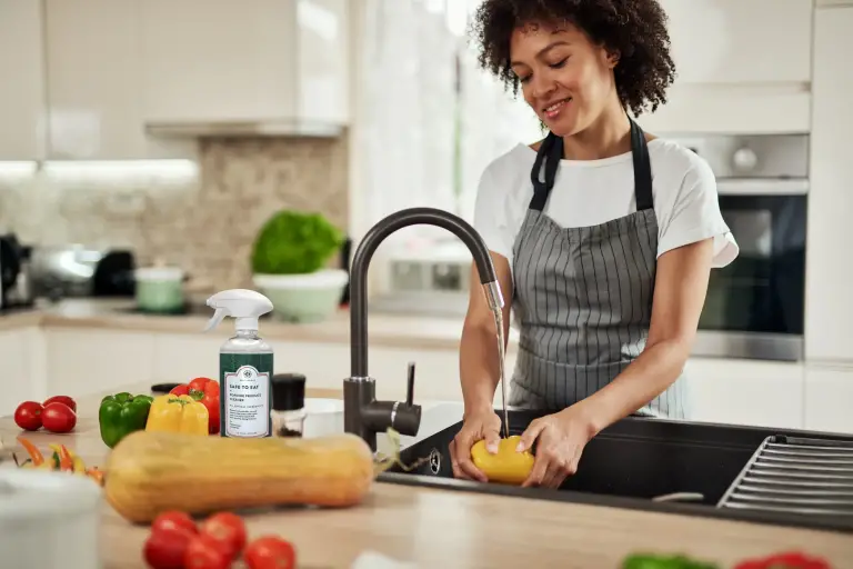 woman cleaning vegetables with DERMAGLOVE's Safe to Eat holistic product. Safeguarding the consumer from chemical runoff that is found in the water supply.